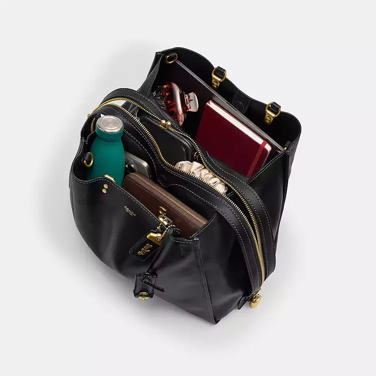 Black leather Coach Rogue Bag 40 crossbody bag with CCX21 logo from The Tiny Bag, showcasing its sleek design and adjustable strap.
