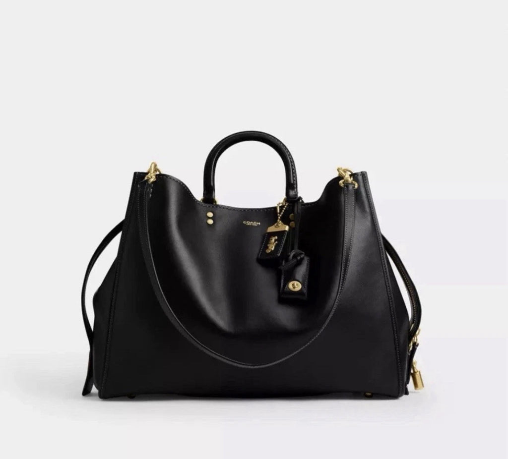 Black leather Coach Rogue Bag 40 crossbody bag with signature CC logo from The Tiny Bag, showcasing its sleek design.
