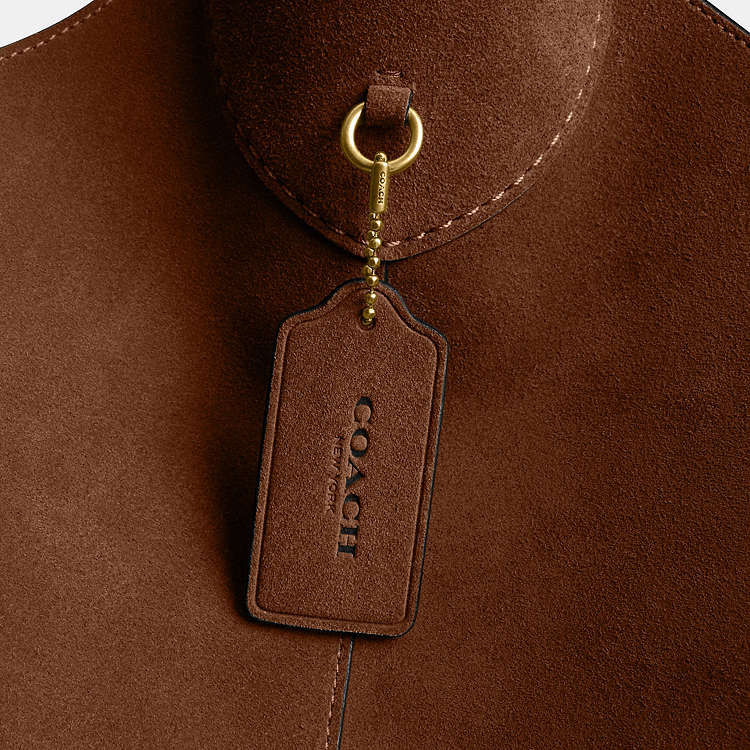 Coach CW636 Suede Brooklyn 39 shoulder bag in warm brown with brass hardware, featuring a sleek suede exterior and shoulder strap.