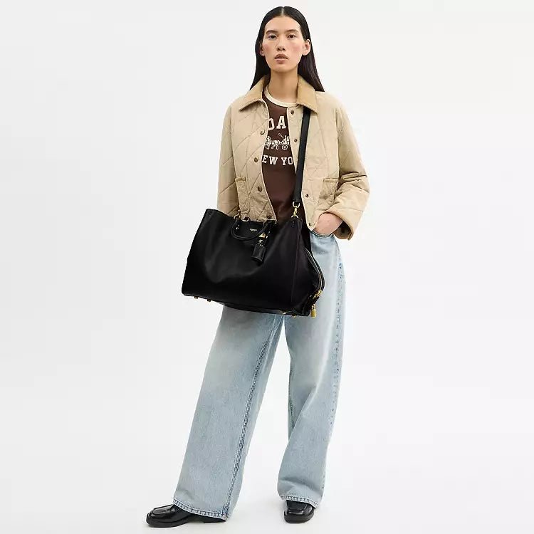 Black leather Coach Rogue Bag 40 crossbody bag with CCX21 logo, stylish and compact, from The Tiny Bag collection.