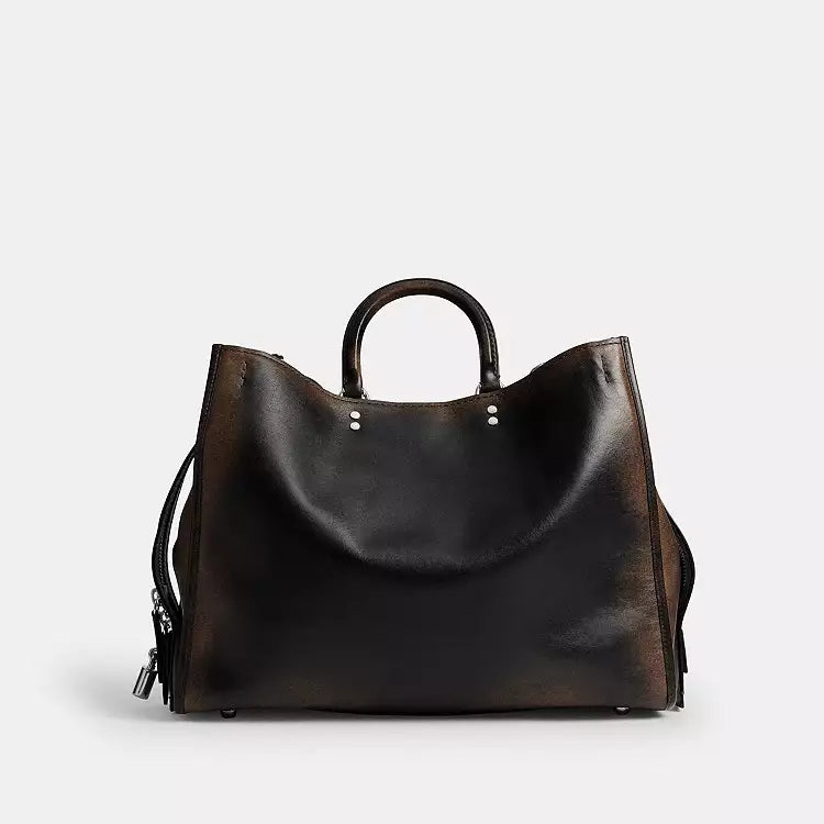 Coach Rogue Bag 40 in loved leather with charms, stylish shoulder bag by The Tiny Bag featuring a sleek design and decorative accessories.