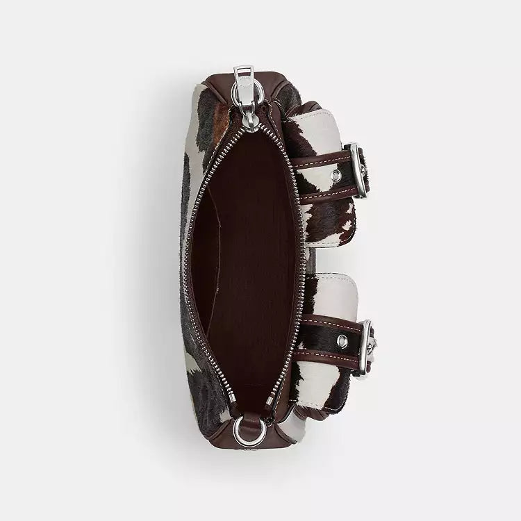The Tiny Bag Coach Ashton shoulder bag with cow print haircalf material, featuring multicolored cow pattern and CCC83 branding.