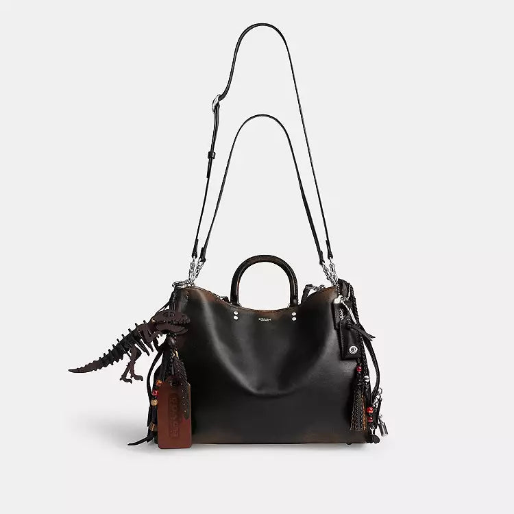 Coach Rogue Bag 40 in loved leather with charms, stylish shoulder bag by The Tiny Bag, featuring a sleek design and decorative charms.