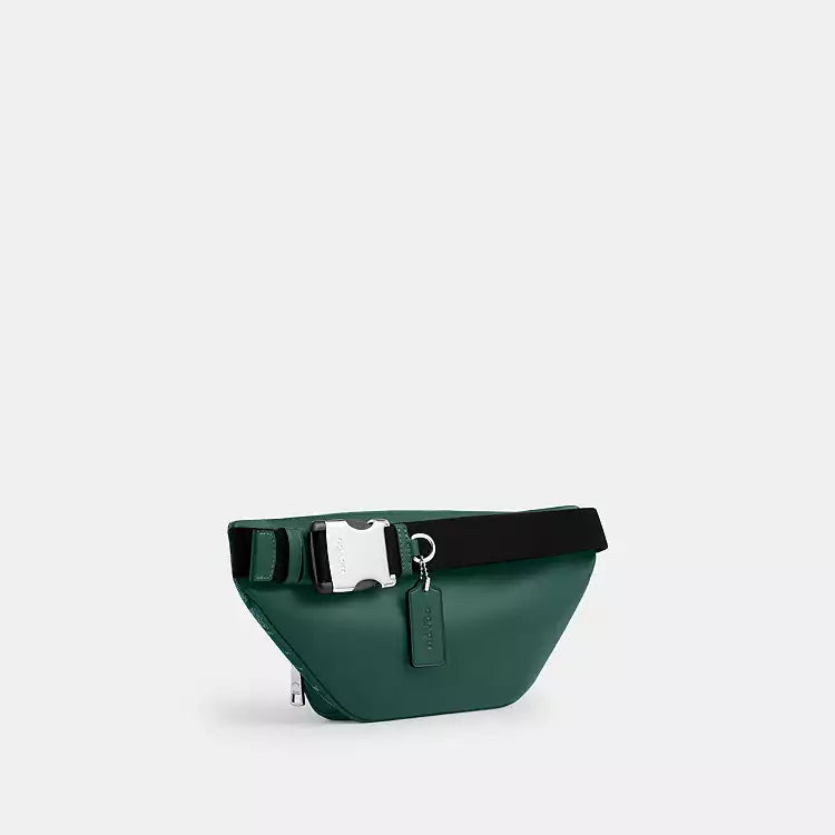 Small Coach Racer belt bag in signature canvas with silver and sea green colors, worn as a stylish crossbody bag.