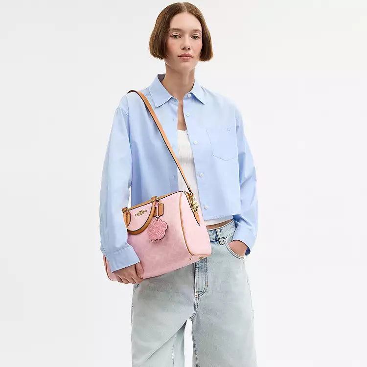 Coach Rowan large signature canvas shoulder bag in powder pink with charms, featuring a spacious design and shoulder strap.