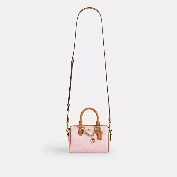 Coach Mini Rowan Crossbody Bag in signature powder pink leather with charms, compact and stylish for everyday wear.