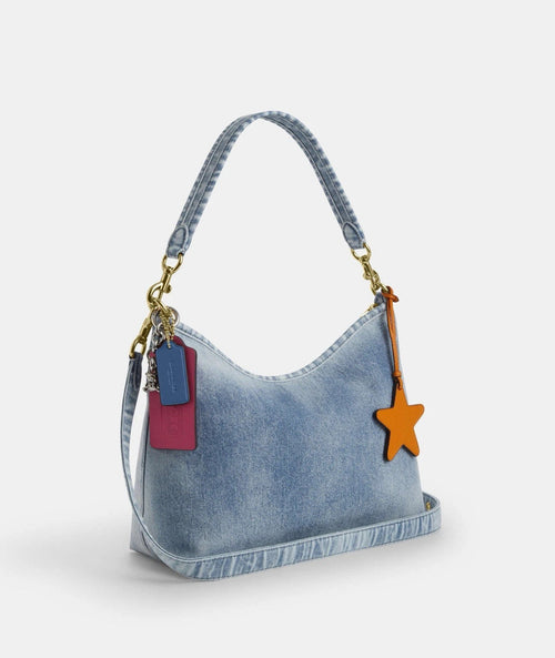 Light indigo Coach CEF26 Laurel shoulder bag from The Tiny Bag with charms and loved denim fabric, detailed view of the bag's design.