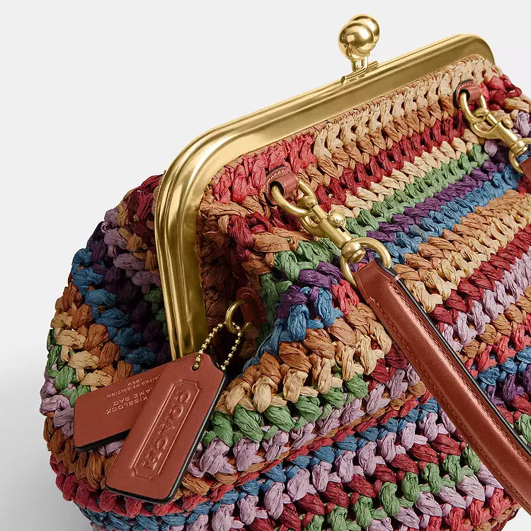 Multicolor straw Coach Kisslock shoulder bag with large size and gold-tone hardware, featuring a classic design and spacious interior.