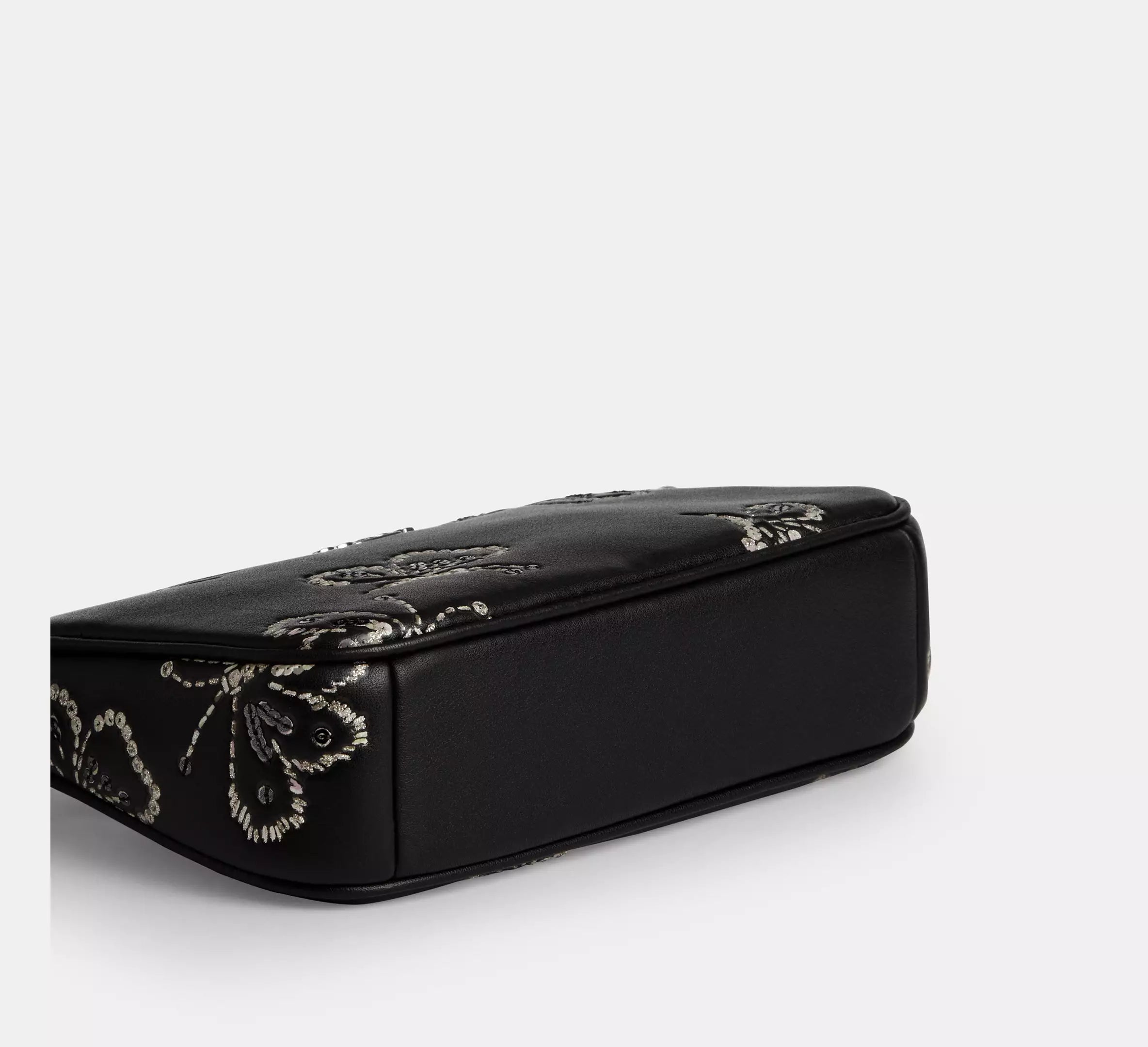 Black leather Coach Nolita 19 shoulder bag with sparkly butterfly print, compact and stylish, from The Tiny Bag collection.