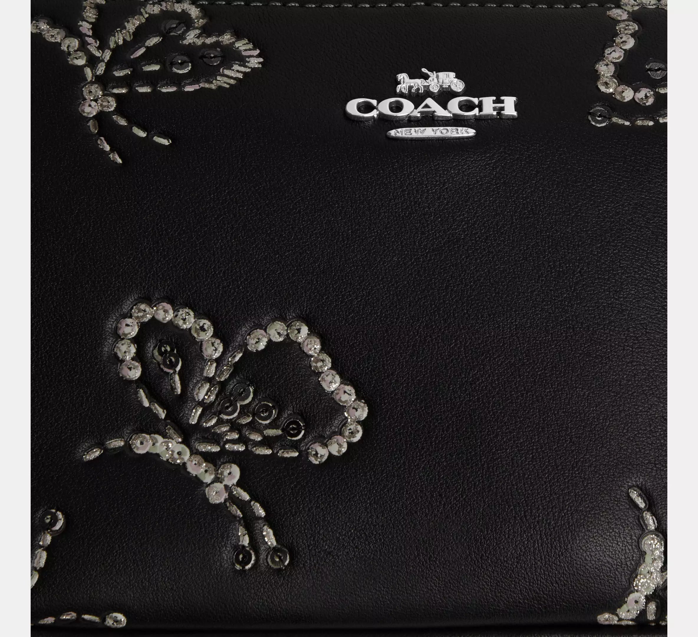 Coach Nolita 19 black leather shoulder bag with sparkly butterfly print and compact design, featuring gold-tone hardware.