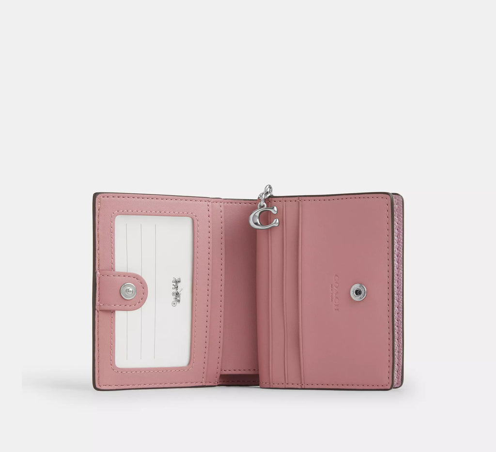 Coach boxed snap wallet and picture frame charm in pink signature canvas, featuring a compact design and gold-tone accents.