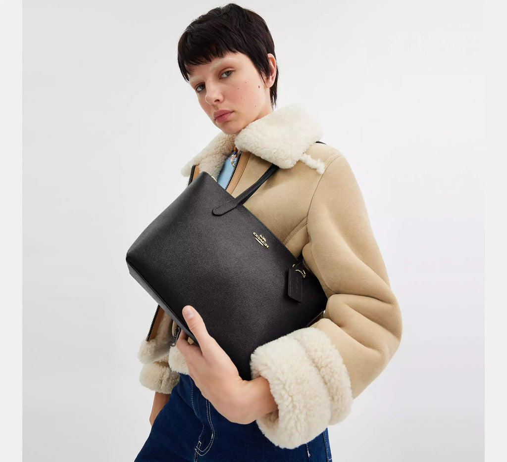 Black leather COACH Fiona Zip Tote Bag with gold accents, featuring sleek design and spacious interior for everyday use.