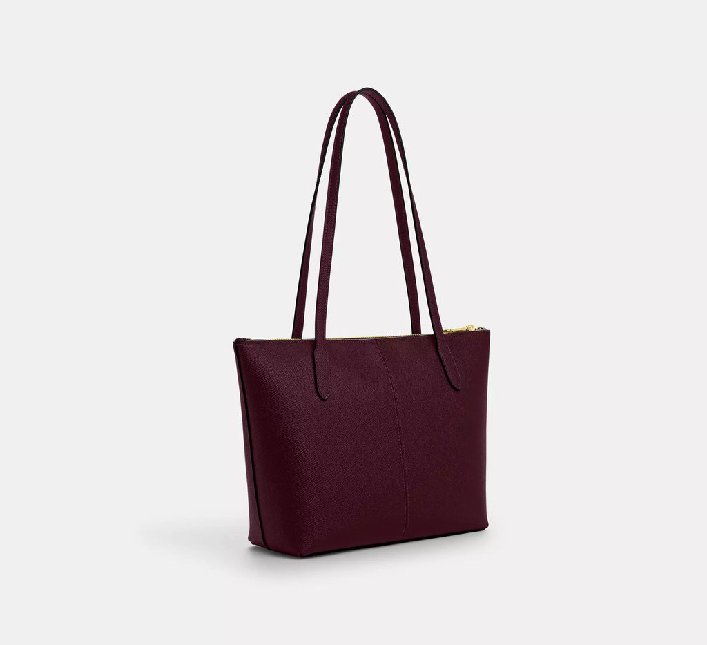 Coach CW395 Fiona zip tote bag in crossgrain leather with gold and dark wine accents, featuring sleek design and sturdy handles.