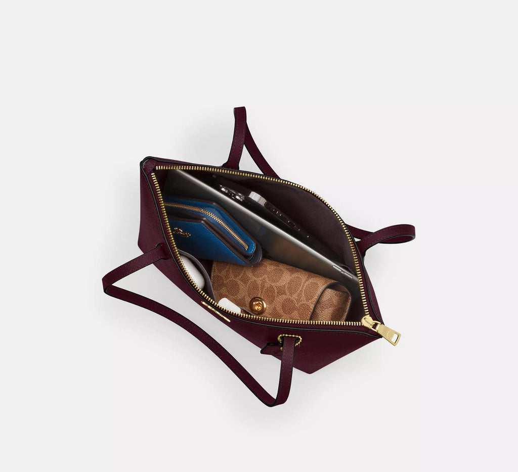 Coach CW395 Fiona zip tote bag in crossgrain leather with gold and dark wine colors, featuring a spacious interior and sturdy handles.