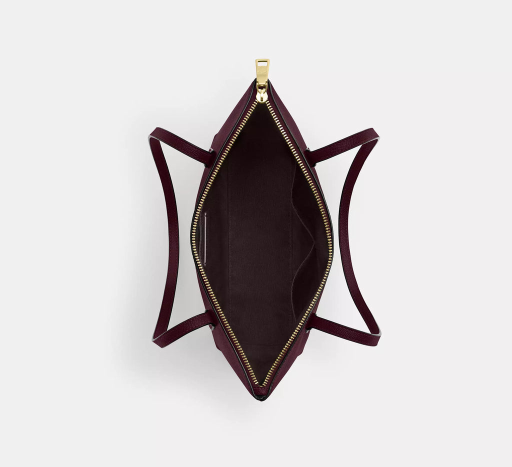 Coach CW395 Fiona zip tote bag in crossgrain leather with gold and dark wine accents, featuring a spacious interior and sleek design.