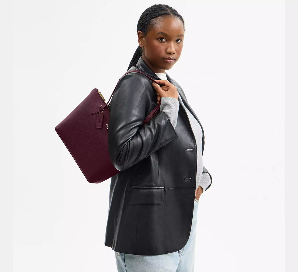 Coach CW395 Fiona zip tote bag in crossgrain leather with gold and dark wine accents, featuring a spacious design and top zipper closure.