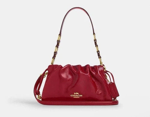 Coach Faye crossbody bag in glazed leather with gold hardware, dark cardinal color, featuring a compact shoulder bag design.